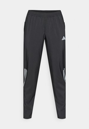 Pantalon de sport noir avec taille élastique, poches latérales et trois bandes blanches sur chaque jambe. Confectionné dans un tissu léger et lisse.
