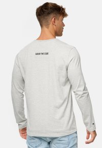 Grå langærmet t-shirt med teksten "WEAR THE CODE" på ryggen, lavet af blødt stof, med rund halsudskæring og afslappet pasform.