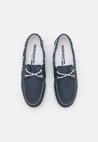 Marineblaue Lederschuhe für Boots mit weißen Schnürsenkeln und Nähten. Sie haben eine gepolsterte Innensohle und eine strukturierte Gummisohle für besseren Halt. Modell: Sebago Marine.
