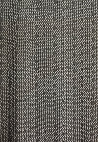 Czarna koronkowa tkanina z misternym wzorem połączonych kwiatowych motywów i kształtów geometrycznych, o delikatnej, finezyjnej fakturze.