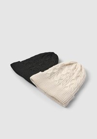 Dwie dziergane czapki beanie: jedna czarna z warkoczowym wzorem, druga kremowa o podobnym wzorze. Obie mają prążkowany mankiet.