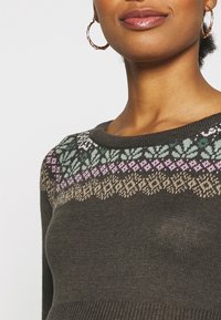 Maglione a maglia verde scuro con un motivo a yoke in tonalità di viola chiaro, verdi e marroni. Collo a coste e texture liscia.