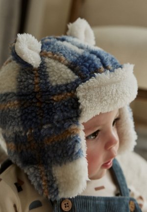 Mėlynos ir baltos languotos flisinės kepurės su purus ausų atvietėmis, pabrėžtomis šviesiai rudos spalvos detalėmis ir minkšta tekstūra. Ideali šilumai.
