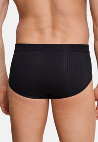 Costumi da bagno per uomini neri, con una texture a coste, vita elasticizzata e un taglio aderente, che mettono in risalto una finitura in tessuto liscia.