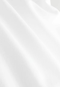 Weißer Stoff mit glatter Textur, der sanfte Drapierungen und einen dezenten Glanz aufweist und sein leichtes und luftiges Erscheinungsbild unterstreicht.