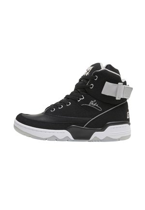 Sneaker high-top bianco e nero con lacci, cinturino alla caviglia, tomaia strutturata e suola spessa progettata per sport o uso casual.