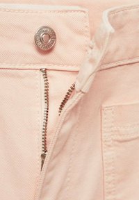 Tissu en denim rose avec un bouton-pression en métal et une braguette zippée, présentant une fermeture éclair argentée et des détails de texture subtils.