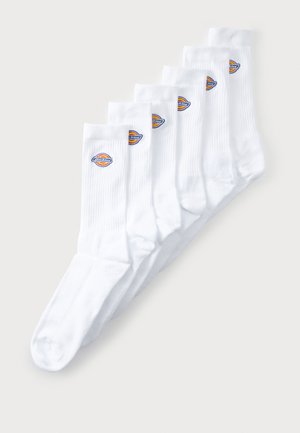Seis pares de calcetines blancos de caña media con puños acanalados, cada uno con un pequeño logo de la marca en colores cerca de la parte superior sobre un fondo claro.