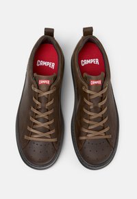 Zapatillas de cuero marrón con puntera redonda, diseño con cordones, plantillas rojas y suelas de goma negras con perforaciones en la parte superior.