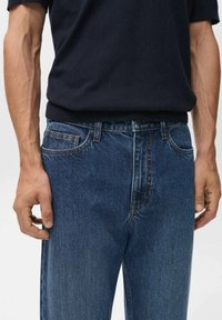 Jeans din denim de culoare albastru închis, cu croială dreaptă, având cusături în contrast, cinci buzunare și închidere cu nasture la talie.
