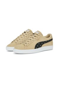 Beige semišové tenisky mají černý akcent s malými vzory, bílou gumovou podrážku a ploché tkaničky. Klasický design s nízkým profilem.