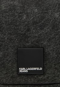 Fekete farmer texturált felülettel, négyzet alakú fekete címkével, amelyre fehér betűkkel van debütálva: "KARL LAGERFELD JEANS".