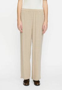 Beige weitgeschnittene Hose mit elastischem Bund, aus leichtem Stoff gefertigt. Bietet eine glatte Textur und einen subtilen, weichen Fall.