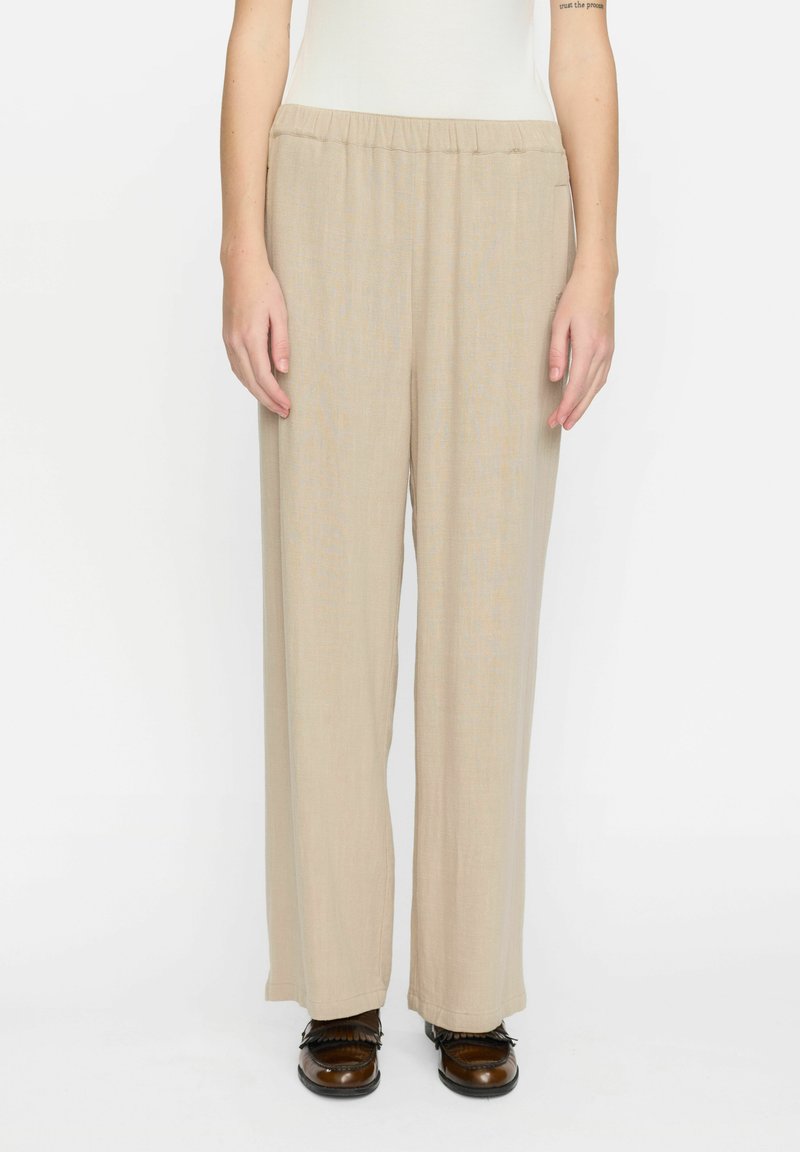 Beige weitgeschnittene Hose mit elastischem Bund, aus leichtem Stoff gefertigt. Bietet eine glatte Textur und einen subtilen, weichen Fall.