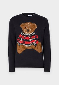 Zwarte gebreide trui met een teddybeerontwerp in bruin, die een rood-zwart gestreepte trui draagt met witte accenten en een ronde halslijn.