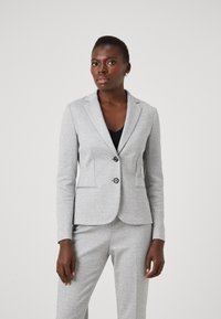 Siv obrabljen blazer z oprijetim krojem, z nazobčanimi reverji, dvema gumboma in stranskima žepoma, v kombinaciji z črnim vrhom spodaj.