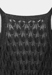 Tissu tricoté noir avec un motif de dentelle ajourée complexe formant des diamants et des formes de feuilles, montrant la partie supérieure du dos avec des bretelles fines.