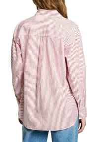 Camicia a maniche lunghe a righe rosse e bianche, con colletto classico e vestibilità rilassata. Tessuto morbido con dettaglio sulla spalla posteriore.