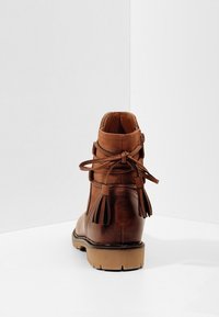 Bottines en cuir marron avec un col en daim, des accents de franges et une semelle en caoutchouc. Présente un design à lacets avec fermeture à glissière à l'arrière.