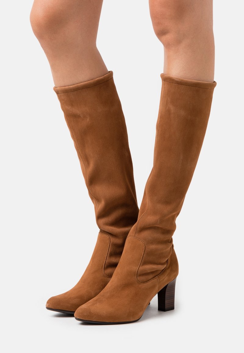 Bottes cuissardes en daim marron à coupe décontractée, bout pointu et talon empilé. Texture lisse sans motifs ni accessoires visibles.
