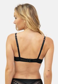 Soutien-gorge noir avec bretelles réglables, fermeture à crochets et œillets, et un design en dentelle transparente le long de la bande. Texture lisse avec un style minimaliste.