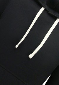 Zwarte hoodie met een voorzak in kangoeroestijl, voorzien van witte trekkoorden en een zachte, gestructureerde stof. Het ontwerp omvat een klassieke pulloverstijl.