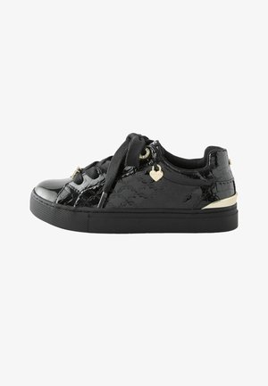 Zwarte lakleren sneaker met dikke zool, brede zwarte veters, gouden hartvormige hanger en gouden accent op de hiel.
