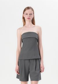 Grå stroppeløs topp med strukturert design og plisserte shorts, laget av teksturert stoff, med rene linjer og minimale detaljer.