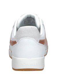 Witte sneakers met een suède hiel, tan accenten en een textuurrubber zool. Merkennaam "SKECHERS" gedrukt op de hiel.