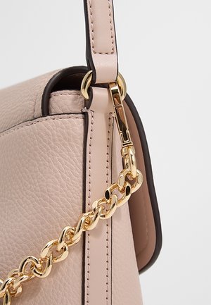 Sac à main en cuir beige texturé avec bandoulière chaîne dorée et détail de fermeture dorée sur un fond blanc épuré.