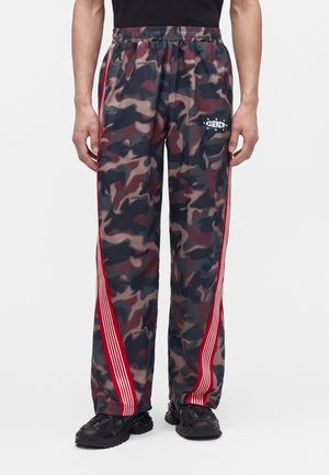 Lockere Herrenhose mit Camouflage-Muster, roten und weißen Seitenstreifen, elastischem Bund und schwarzen Sneakers.