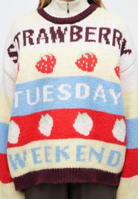 Πλεκτό πουλόβερ με πολύχρωμες ρίγες και κείμενο "STRAWBERRY TUESDAY WEEKEND", διακοσμημένο με μοτίβα φράουλας· άνετη, oversized σχεδίαση.
