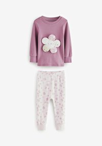Chemise longue à manches violettes avec un motif floral comportant des pétales de couleur claire, associée à un pantalon blanc orné de pois et de fleurs roses.