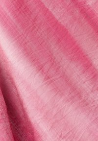 Różowy materiał z ukośnymi jasnymi i ciemnymi paskami, ukazujący miękką, pogniecioną teksturę.