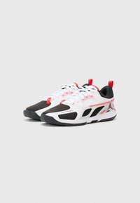White and black athletic shoes with red accents, featuring a mesh upper, textured soles, and prominent branding on the side.