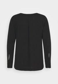 Blouse noire à manches longues avec encolure ronde, pli central dans le dos et poignets boutonnés avec petites fentes.