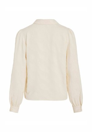 Blusa color crema con finitura testurizzata, caratterizzata da un colletto classico, maniche lunghe a sbuffo e polsini con bottoni. Vista posteriore mostrata.