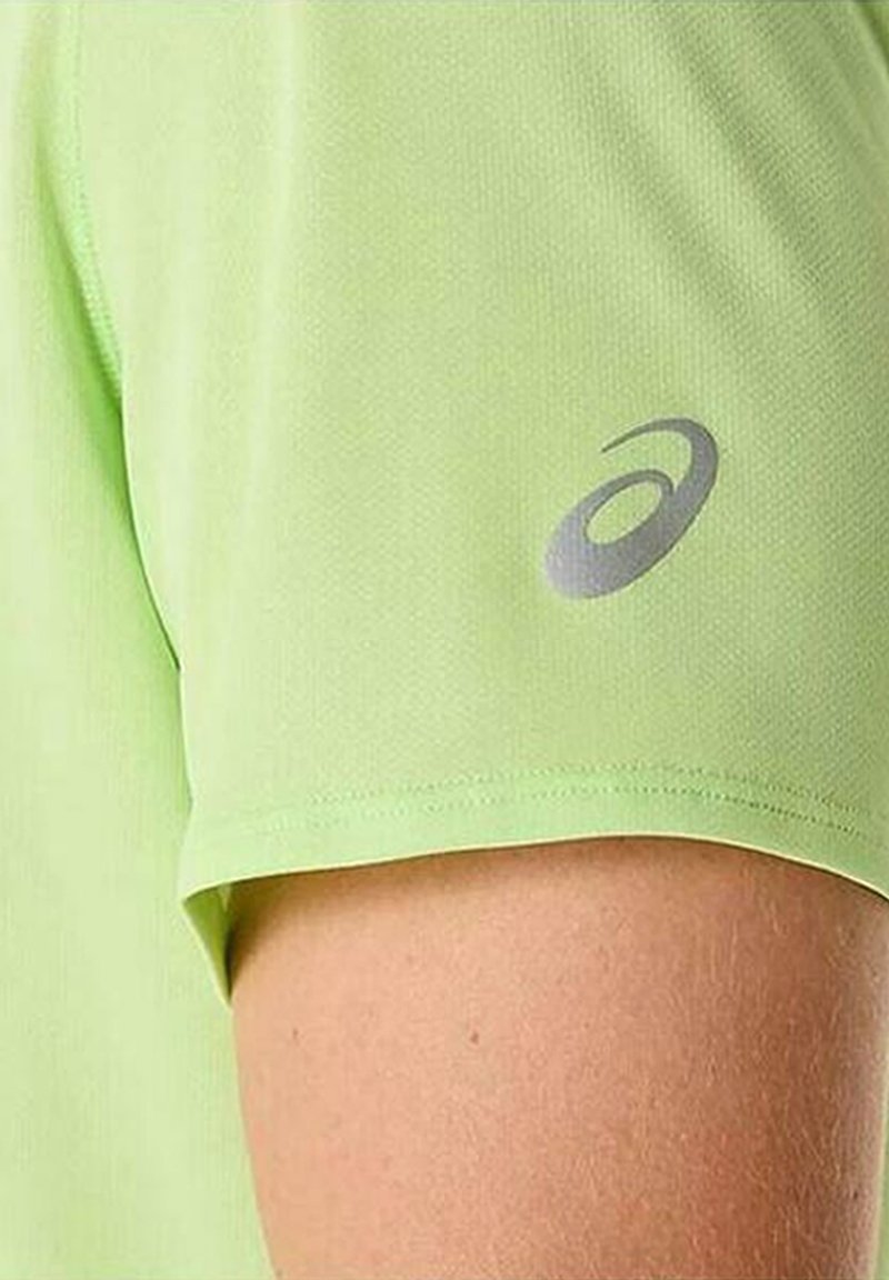 Maglietta sportiva verde chiaro a maniche corte, realizzata in un tessuto testurizzato e traspirante. Presenta un logo grigio sulla manica.