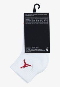 Calcetines tobilleros blancos de mezcla de algodón, con un logo rojo de Jumpman. Viene con una etiqueta negra que muestra la talla y la información de cuidado.