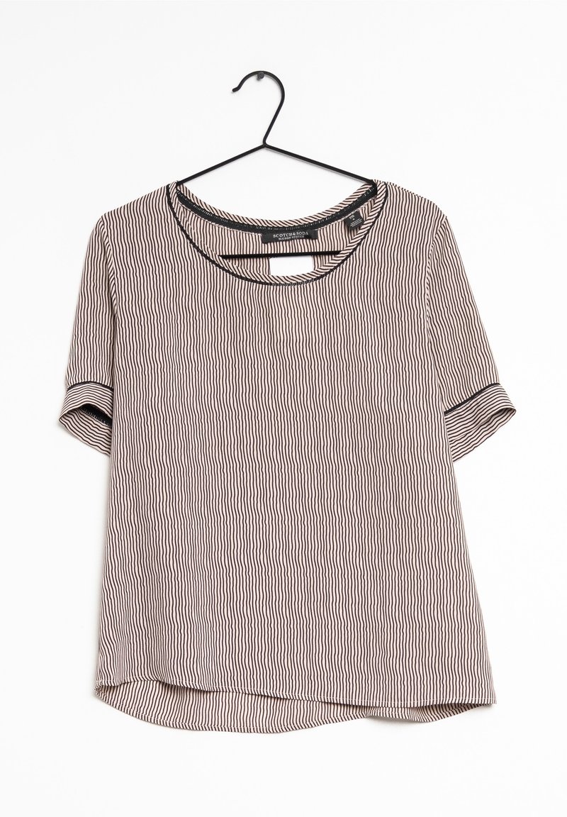 Blouse beige et noire à manches courtes à rayures verticales avec bordure noire sur le col et les poignets, suspendue sur un cintre noir.