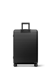 Valise noire avec une surface texturée comportant des rainures horizontales, une poignée rétractable et quatre roulettes pour la mobilité.