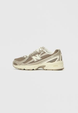 Zapatilla New Balance 740 beige y crema con parte superior de malla, cordones blancos y amortiguación ABZORB sobre fondo blanco.