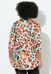 Top con stampa leopardata multicolore con maniche a tre quarti, caratterizzato da accenti arancioni, neri e turchesi su uno sfondo chiaro. Texture morbida.