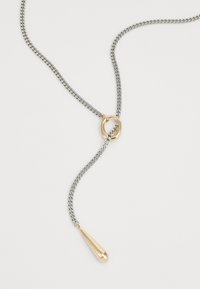 Collier en chaîne argentée avec une boucle ovale en or et un pendentif en forme de goutte d'or suspendu à la chaîne.