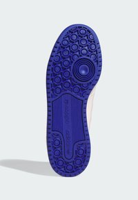 Shoe outsole in vibrant purple, featuring circular grip patterns, a central circular accent, and "adidas" branding with textured lines.