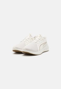 Witte sportschoenen met bovenwerk van gaas, slank ontwerp, ronde neus, dunne veters en lichtbruine rubberen zool met cirkelvormige accenten.