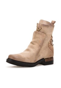 Beżowe skórzane botki za kostkę z okrągłym noskiem, sznurowaniem, ćwiekami po bokach i czarną gumową podeszwą.