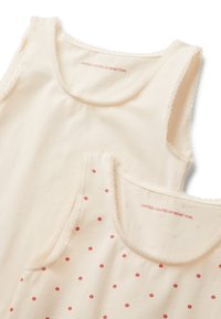 Due top senza maniche da donna in crema, uno tinta unita e l'altro con pois rossi, entrambi con bordi in pizzo e etichetta "United Colors of Benetton".