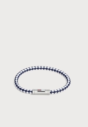 Gevlochten marineblauw en wit koordarmband met een strak zilveren magnetische sluiting op een effen lichte achtergrond.
