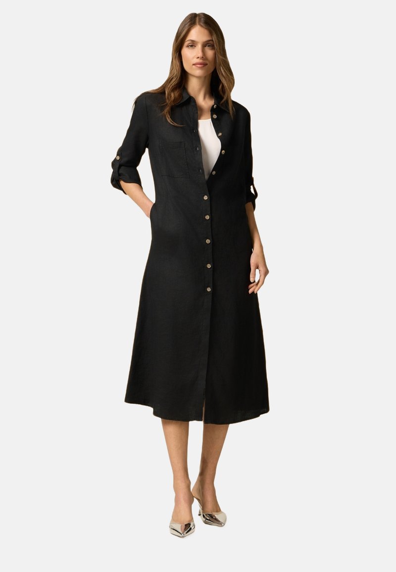 Schwarzes Leinenhemdkleid mit Knopfleiste, hochrollbaren Ärmeln, einer Brusttasche und knielanger Länge. Es hat eine gerade Silhouette und eine subtile Textur.